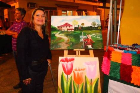 Val ao lado de algumas das pinturas em tela que ensina em seu ateliê, em Piúma-ES | Foto: Arquivo Pessoal