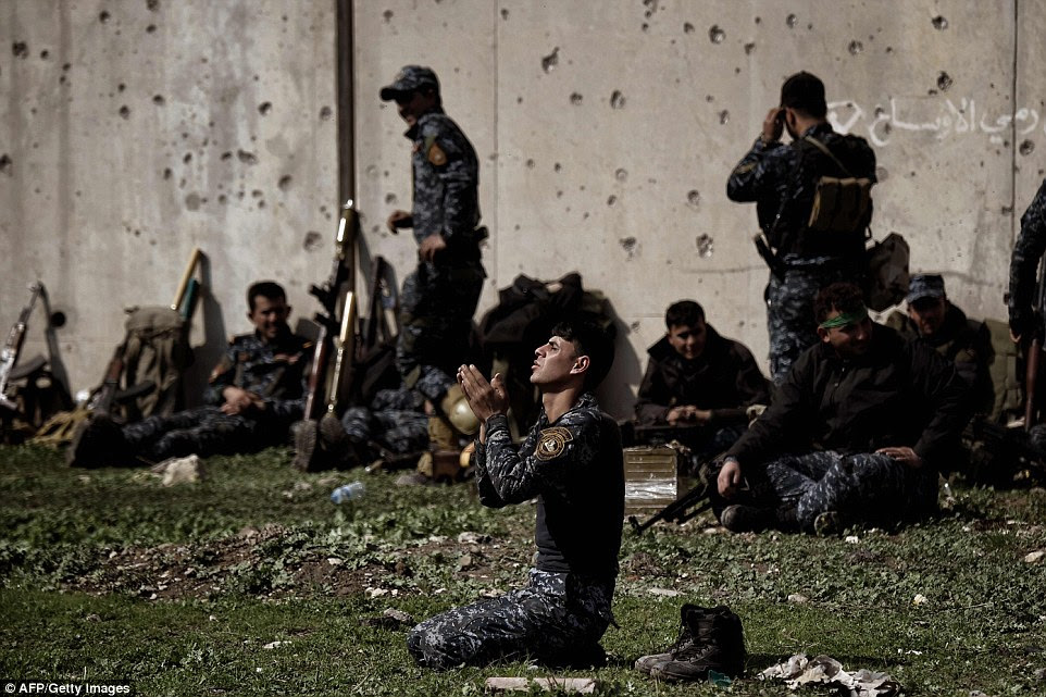 A member of the Iraqi police prays as Iraqi forces clash with Islamic State (IS) group fighters in Mosul on March 5