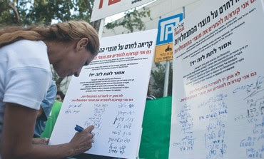 Woman signs Peace Now petition against settlements