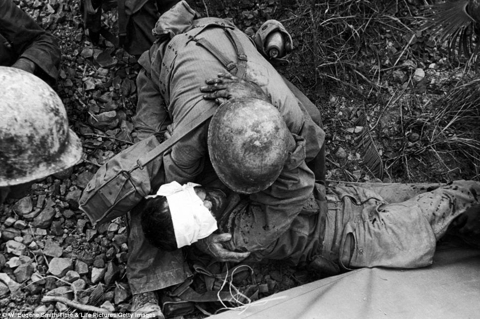 Brothers in arms: On the Marianas Islands, an American soldier comforts a wounded comrade during the fight to take Saipan from Japanese troops