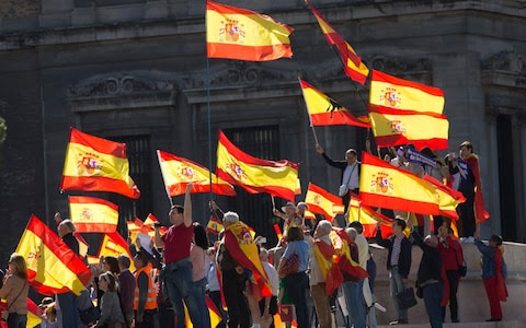 People wave Spanish flags during a mass protest by people angry with Catalonia's declaration of independence