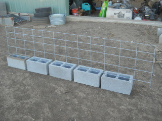 Pig fence piece in place on cinder blocks