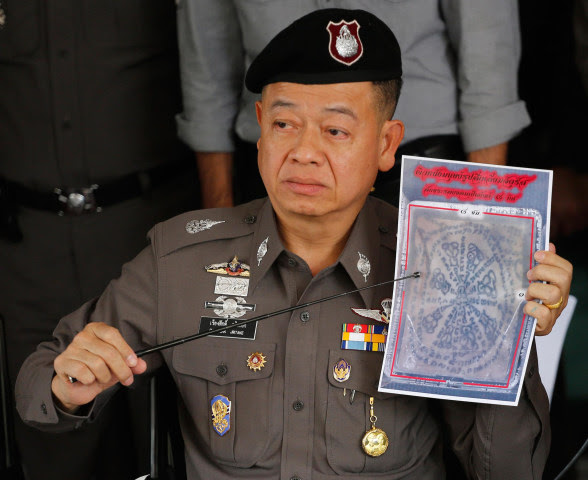 Image: Thai police officer shows a picture of a tattooed human skin