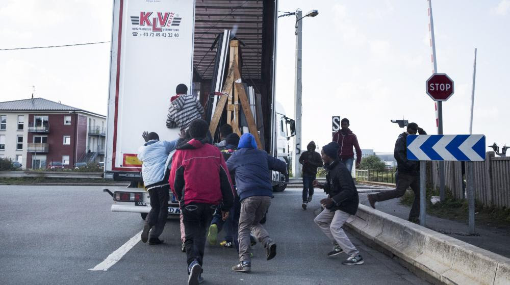 Des migrants profitent du fait qu'un camion &agrave; destination de l'Angleterre s'arr&ecirc;te &agrave; un stop pour tenter de s'introduire &agrave; l'int&eacute;rieur, le 9 octobre 2014, &agrave; Calais.