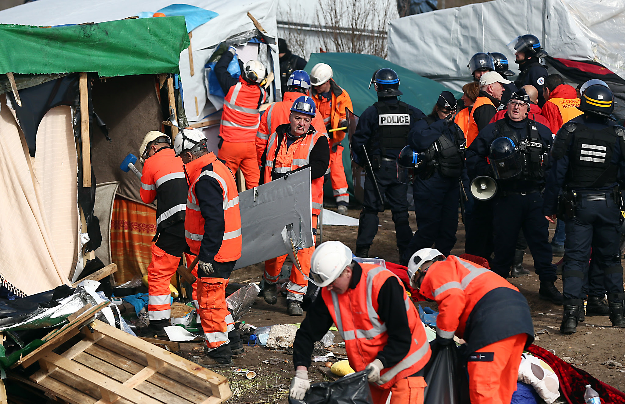 Destruction Of Calais Jungle Camp Begins...CALAIS, FRANCE - FEBRUARY 29:  Workers and police officers clear part of the 'jungle' migrant camp on February 29, 2016 in Calais, France  The French authorities have begun dismantling part of the migrant encampment in the northern French town of Calais and relocating people to purpose-built accommodation nearby. 
