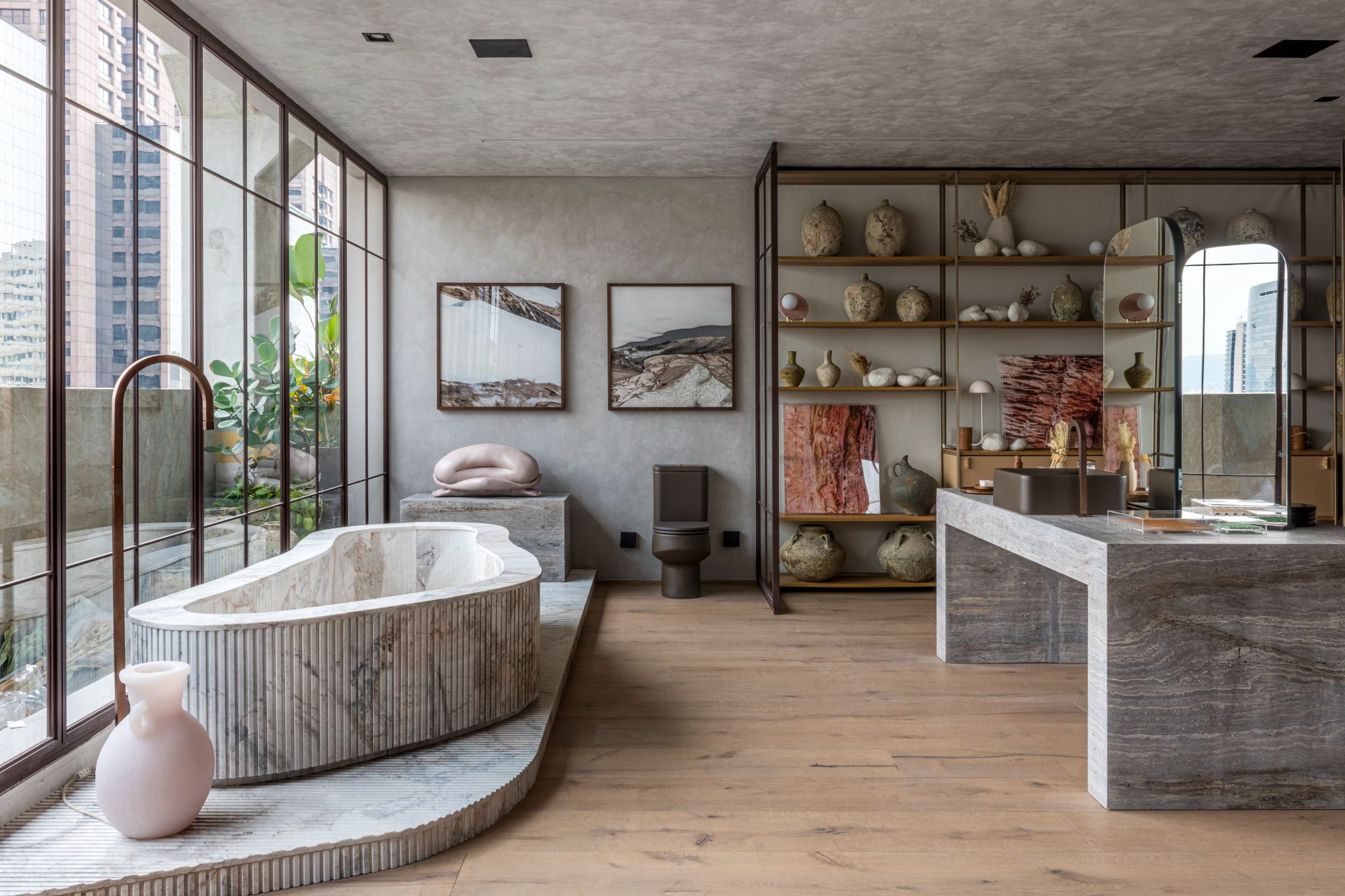 Banheiro destacado por suas curvas, texturas, formas irregulares e pelo uso de materiais naturais, como o mármore canelado na banheira e madeira no piso.