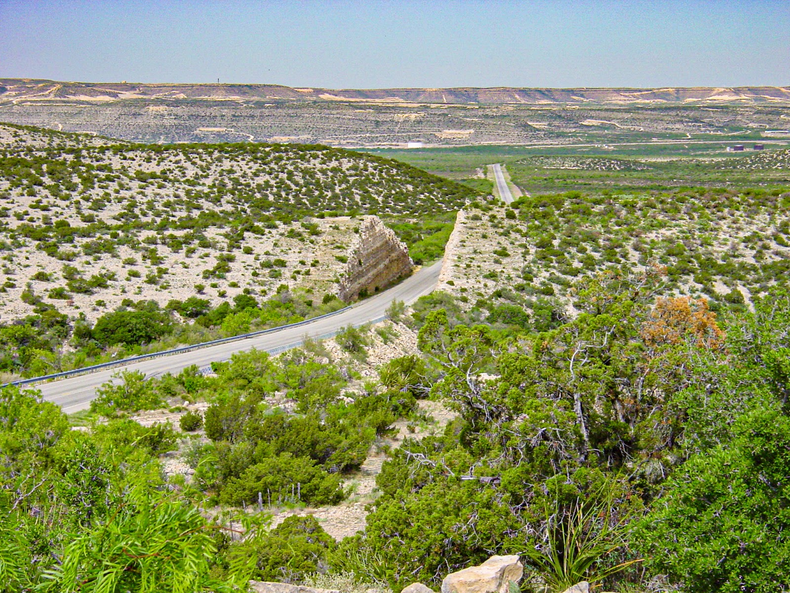 A desert highway is cut through a small hill. 