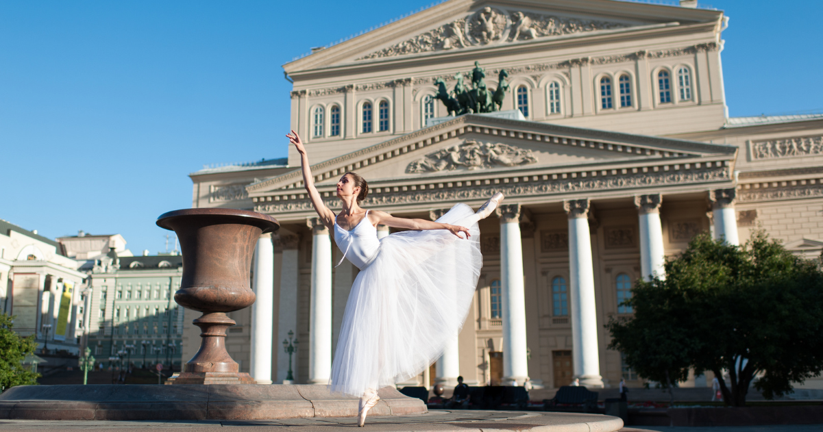 Bolshoi ballerina dances an en pointe arabesque in front of the Russian ballet theater.