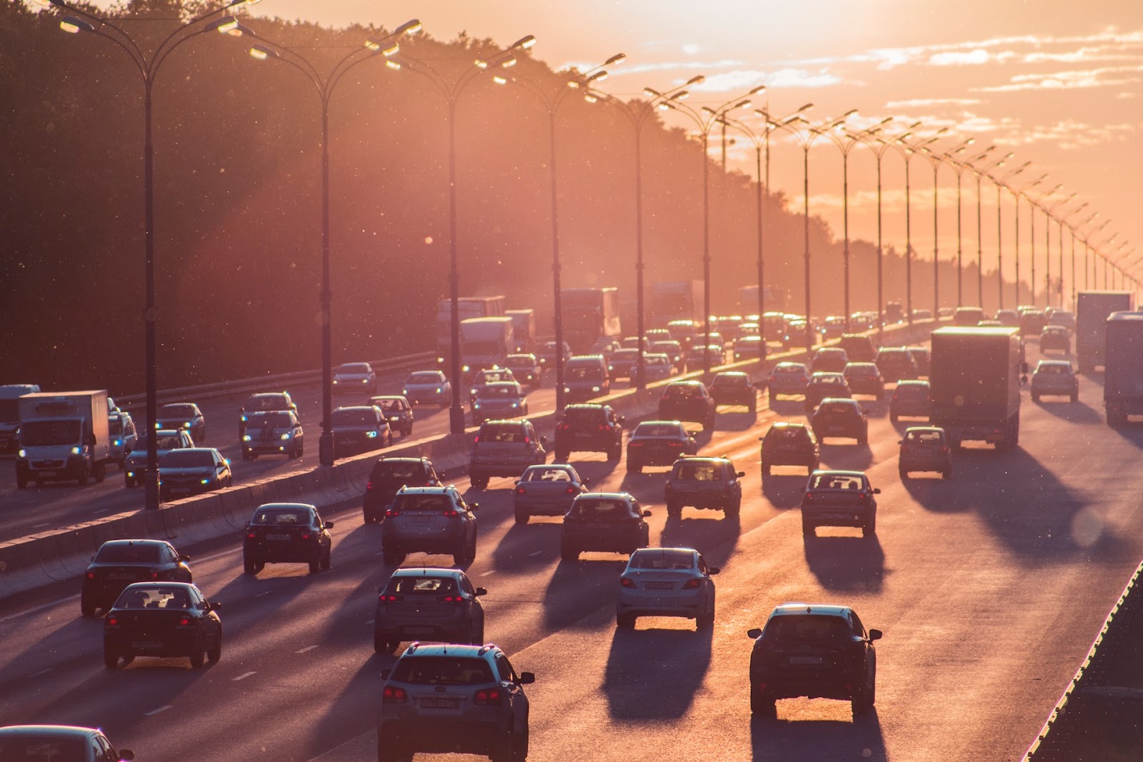 A imagem mostra uma rodovia que está repleta de carros. Na foto, é possível ver seis faixas de um lado, nas quais os carros estão de costas para a imagem. Além disso, no canto esquerdo há mais carros, que são vistos de frente. 
