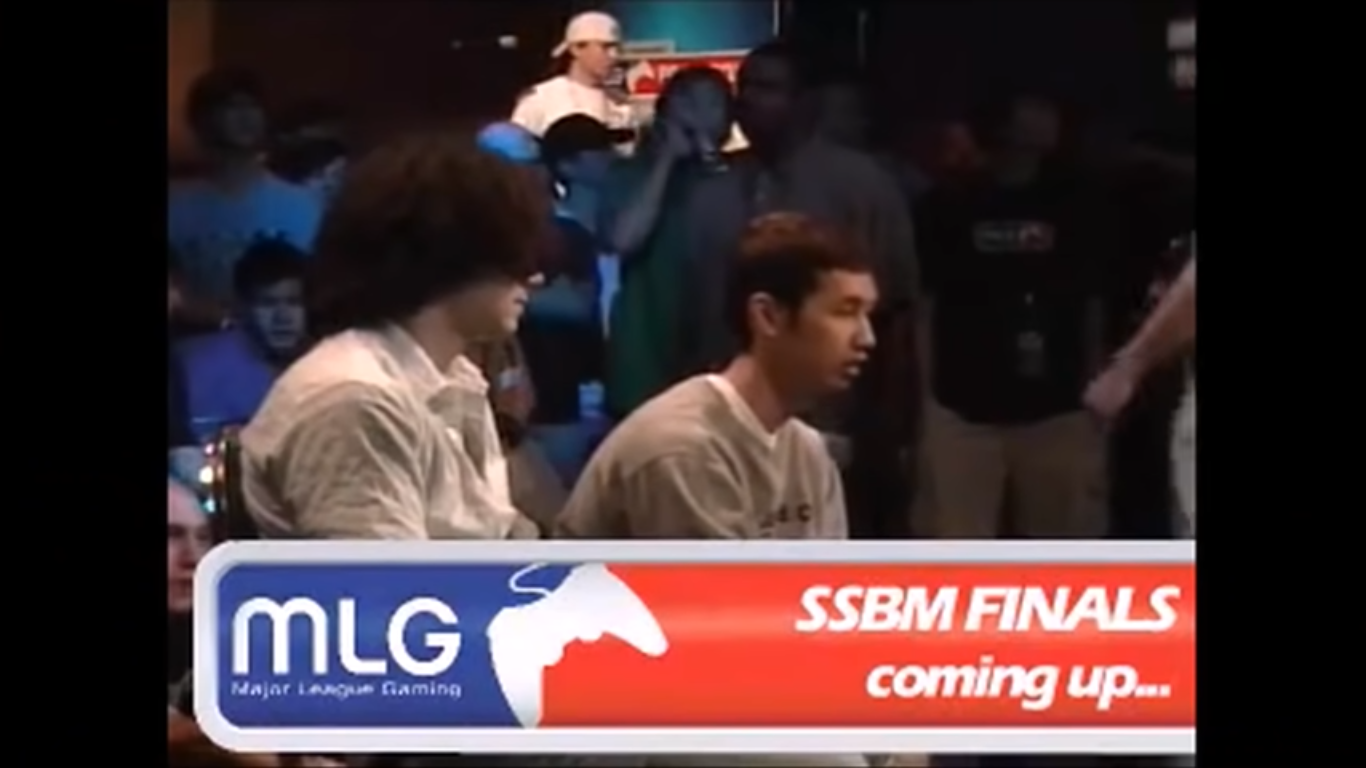 A still from The Smash Brothers. Two male gamers compete in a tournament. There's a bright red MLG chyron below them.