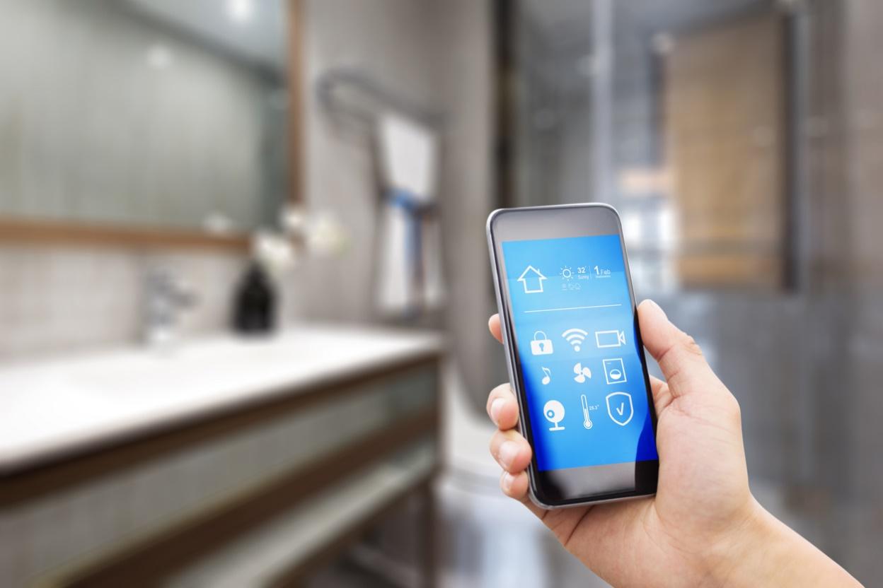 Hand holding a smart device to control fixtures in educational institutes' smart restrooms