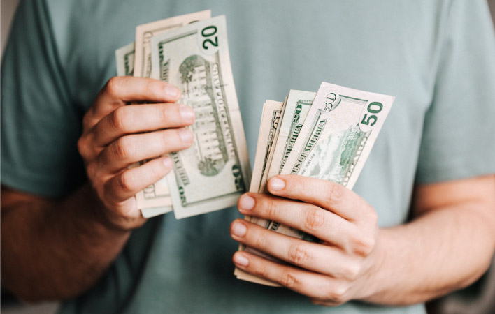 A man holds several large bills in his hands, counting out how much it will cost to pay for his move.