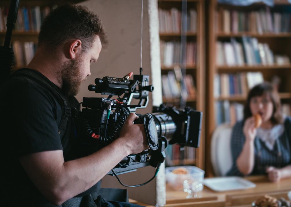 Back view of a videographer with a camera in his hands on a set