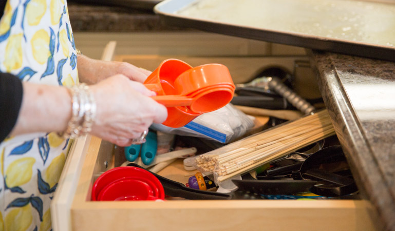 A woman organizing her kitchen junk drawer