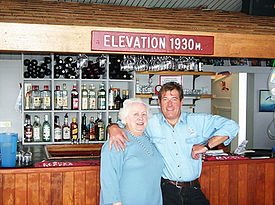 2 people posing for a picture in front of a bar in the Thredbo Alpine Museum