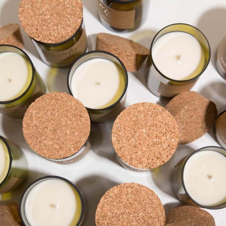 Overhead view of eco-friendly candles in glass containers, topped with natural cork lids.