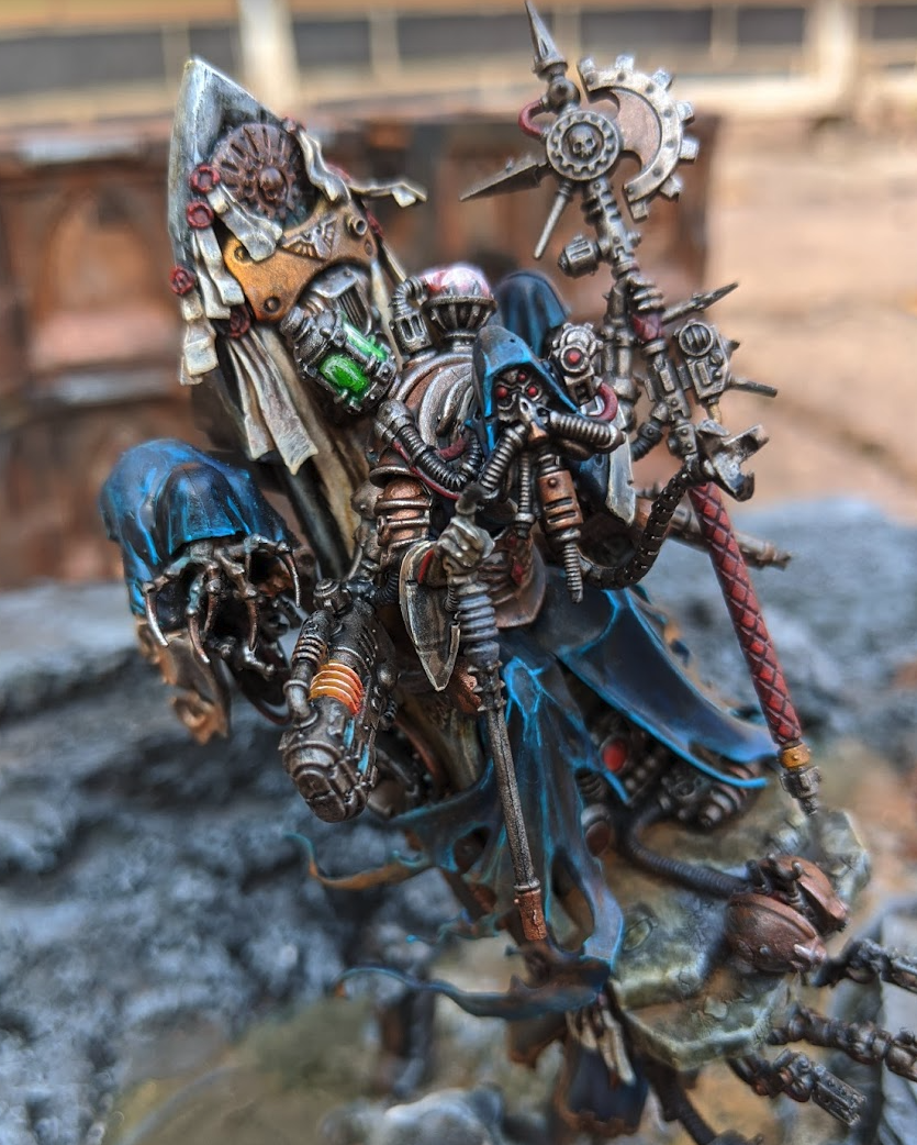 An Ad Mech Tech Priest mixed with a Nighthaunt Craven King model. A flying mechanical throne with attendants on either side clad in blue robes