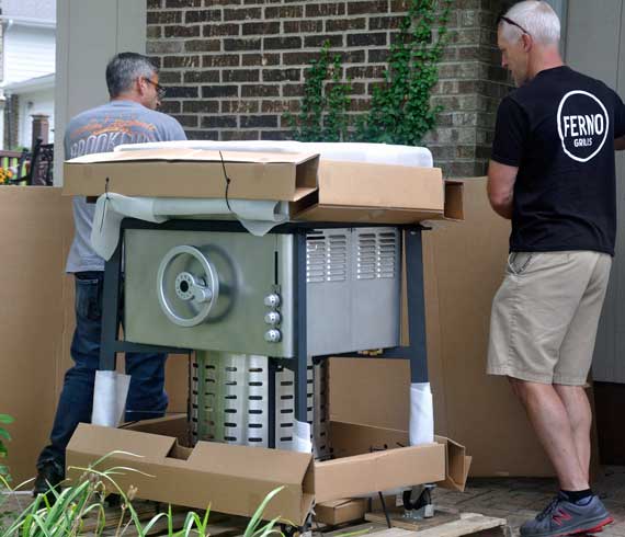 Two men unpack a shiny gas grill