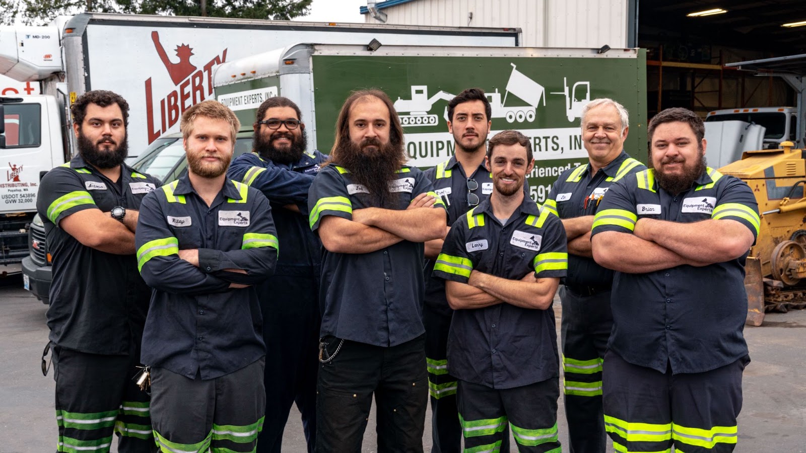 A team of mechanics smiling with their arms folded, all in front of Equipment Experts equipment