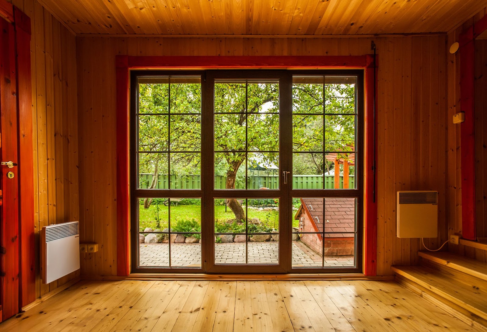 pomieszczenie z dużym, drewnianym oknem tarasowym