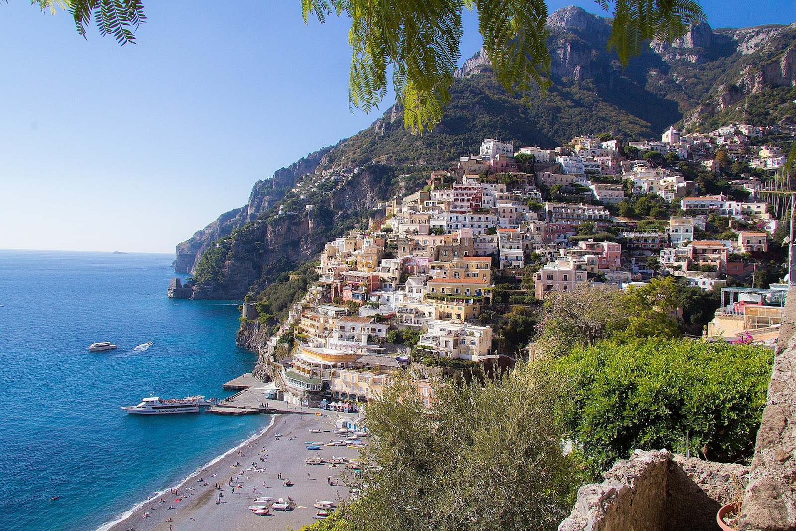 amalfi coastal village beach tourists and ships traditional italian village on seaside cliff hills in background