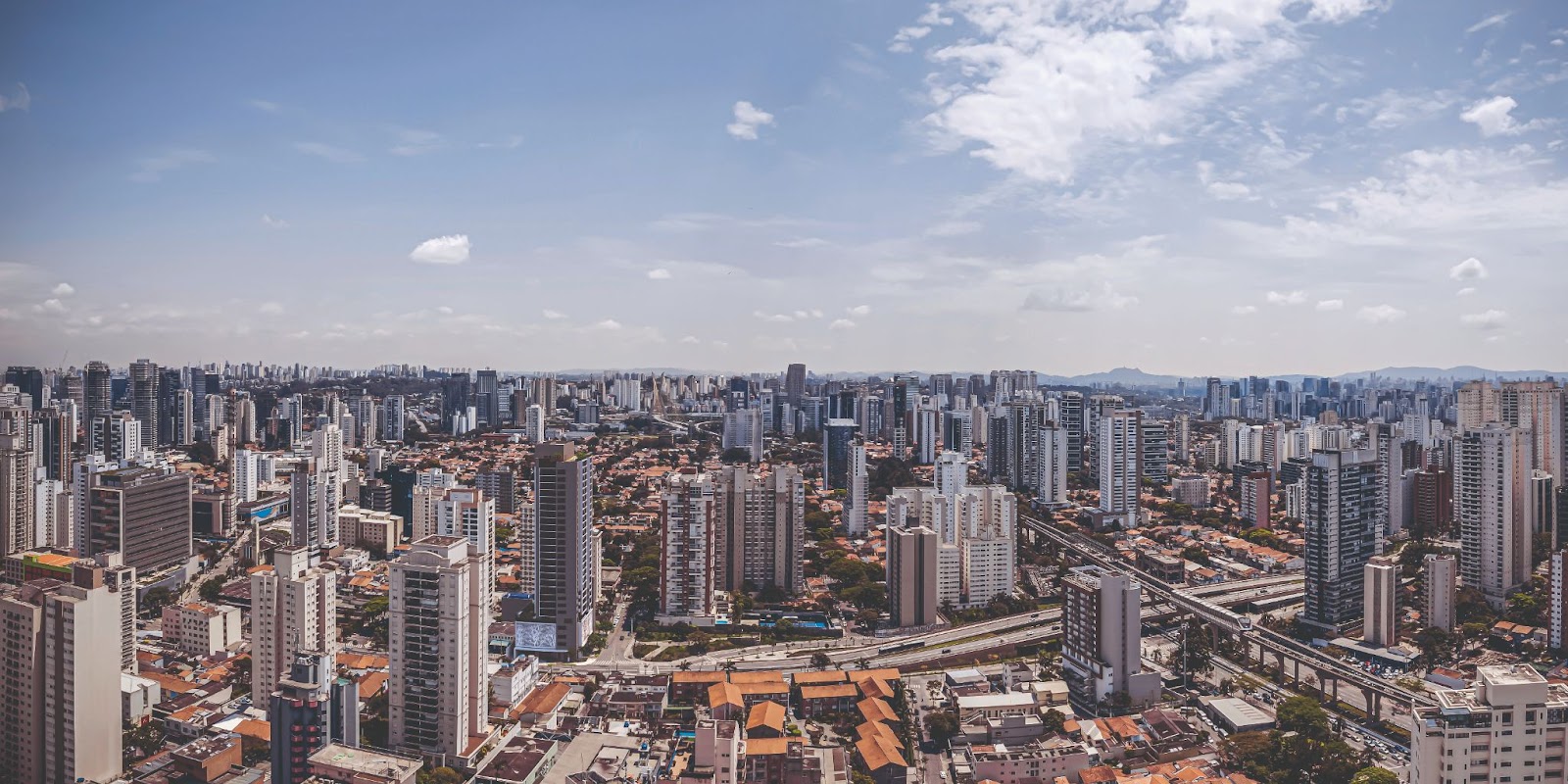 Foto aérea dos melhores bairros de São Paulo para morar. Com muitos prédios e um céu meio conza.