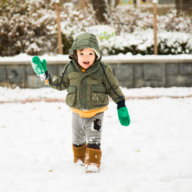 Toddler girl playing in snow in her winter coat and boots