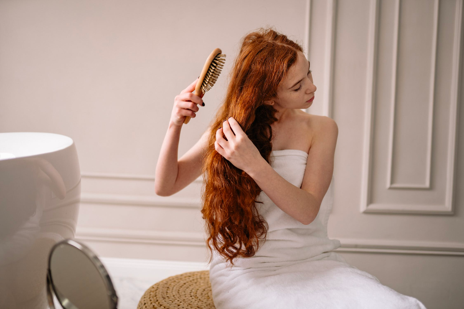 A woman holding on to a hair brush combing her hair