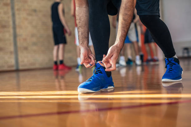 Getting ready for a good game! Shot of a basketball player tying laces on the court. basketball shoes stock pictures, royalty-free photos & images
