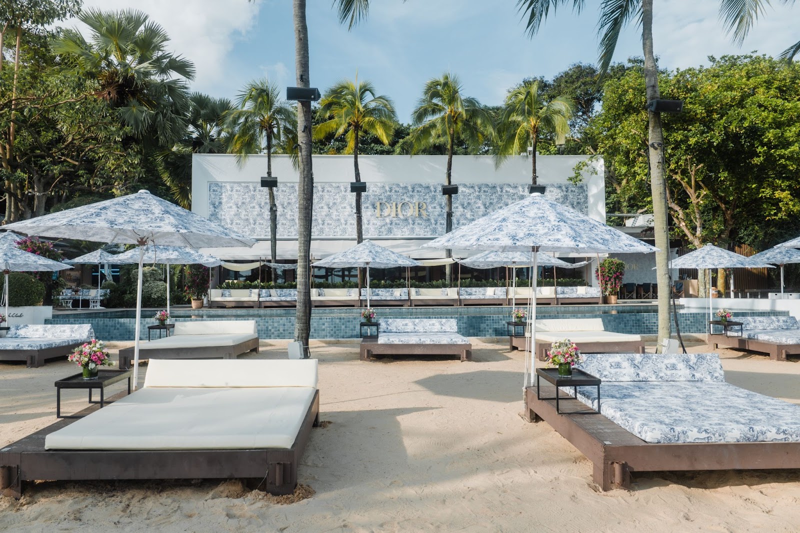 Dior summer campaign Dioriviera event at Tanjong Beach Club, Singapore with daybeds and parasols in toile de jouy sauvage. 