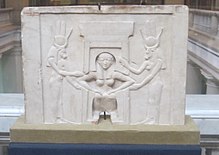 Plaque showing a woman squatting while cow-headed women stand at either side