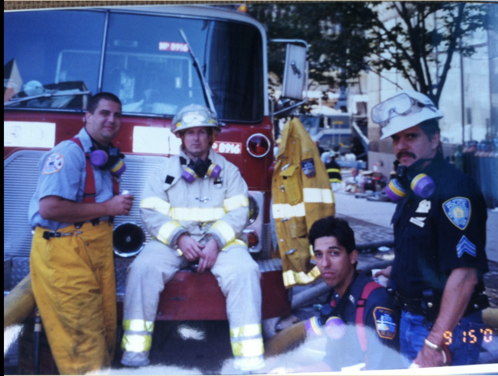 A first responder team sits together beside a fire truck