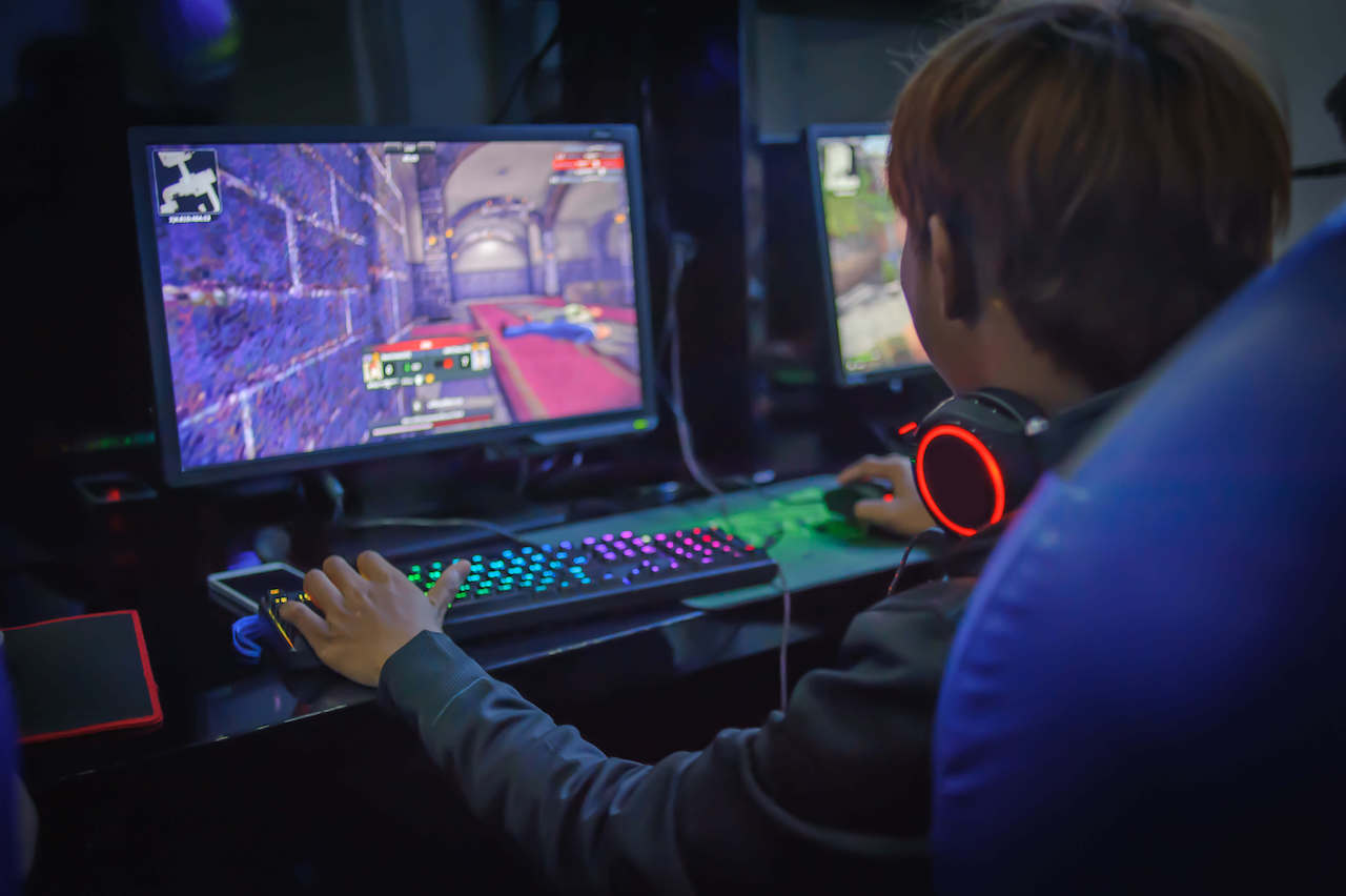 A child playing a video game in a computer cafe.