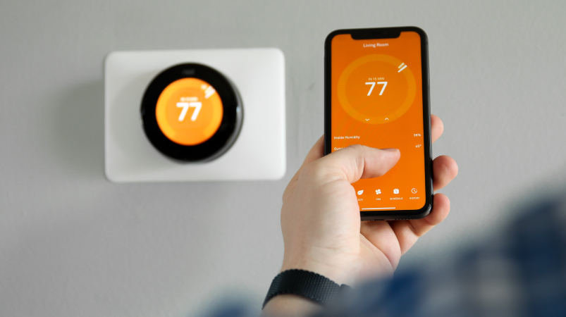 A person using their phone to set their smart thermostat
