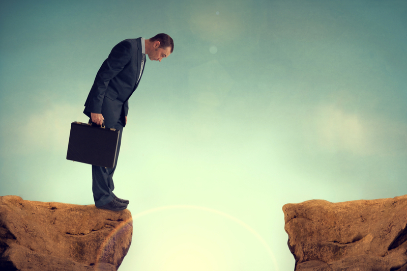 Businessman standing in front of a gap between two rocks - concept of a leadership gap