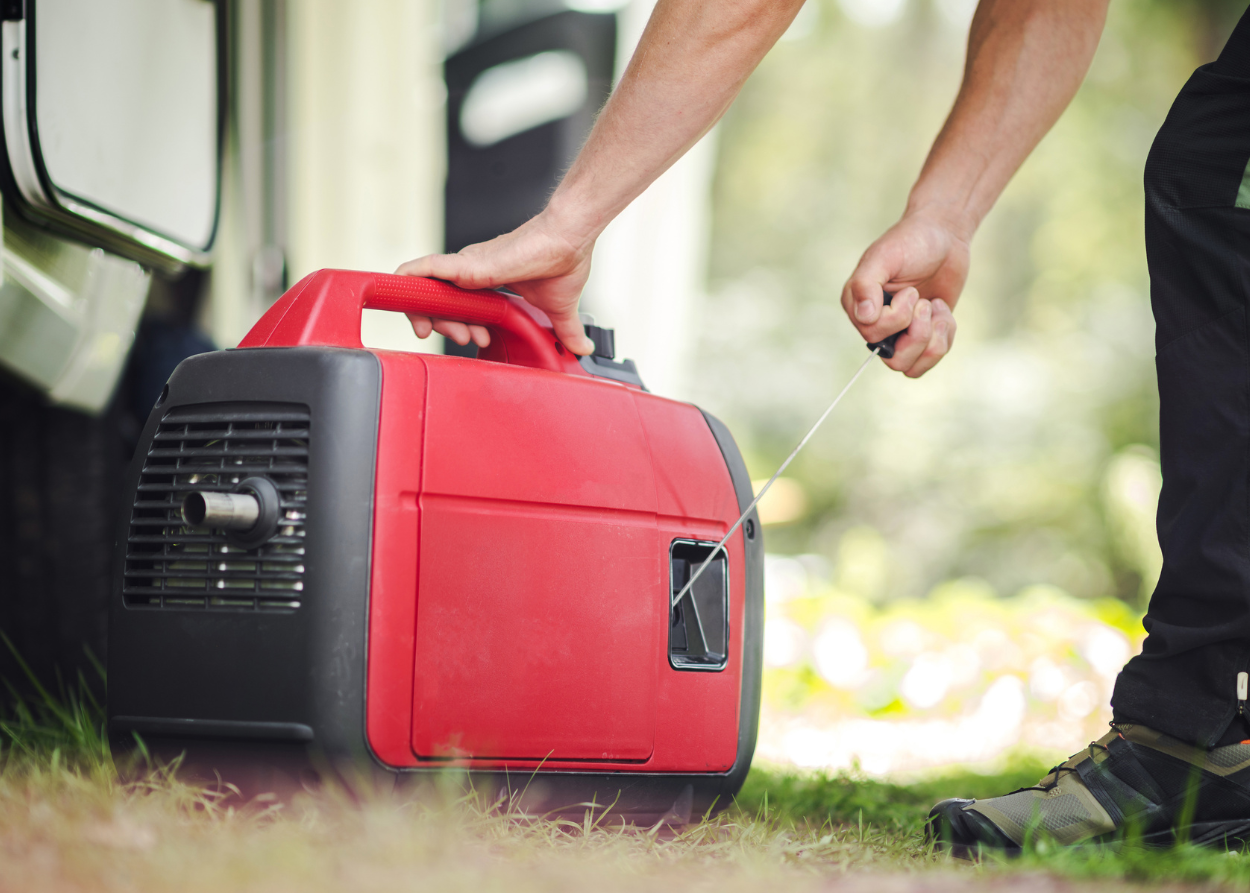 A person pulling the starter cord on a red generator.
