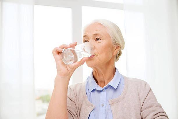 happy senior woman with glass of water at home age, health care and people concept - happy senior woman with glass of water at home elderly drinking water stock pictures, royalty-free photos & images