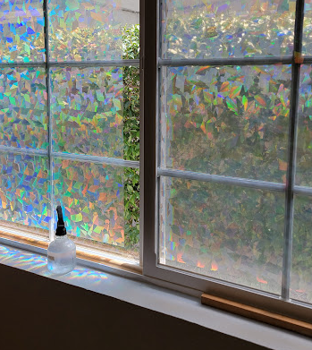 Photo of windows with holographic sheets of prism covering most of the windows and obscuring the view to outside.