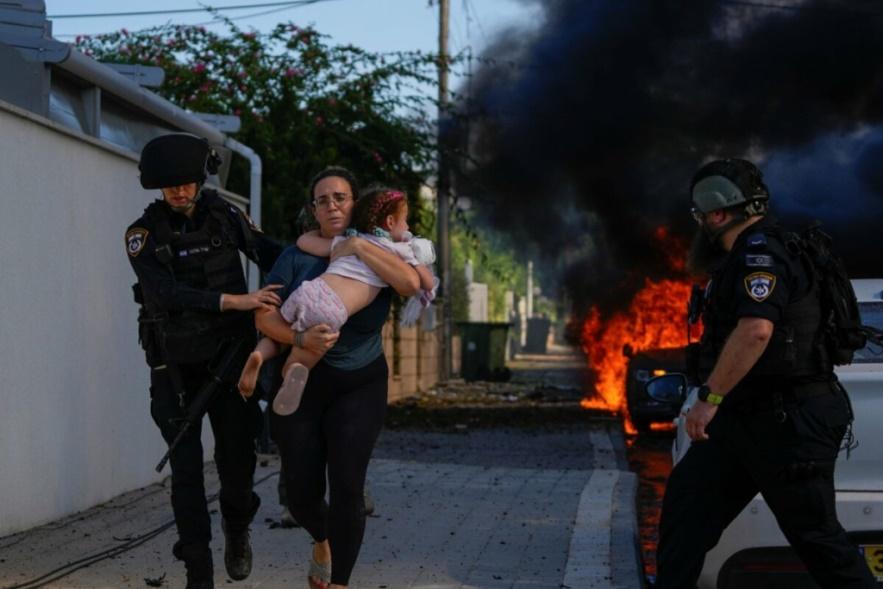Các cảnh sát sơ tán một phụ nữ và một trẻ nhỏ khỏi địa điểm bị trúng hỏa tiễn bắn từ Dải Gaza tại Ashkelon, miền Nam Israel, hôm thứ Bảy 07/10/2023. (Ảnh: AP Photo/Tsafrir Abayov)