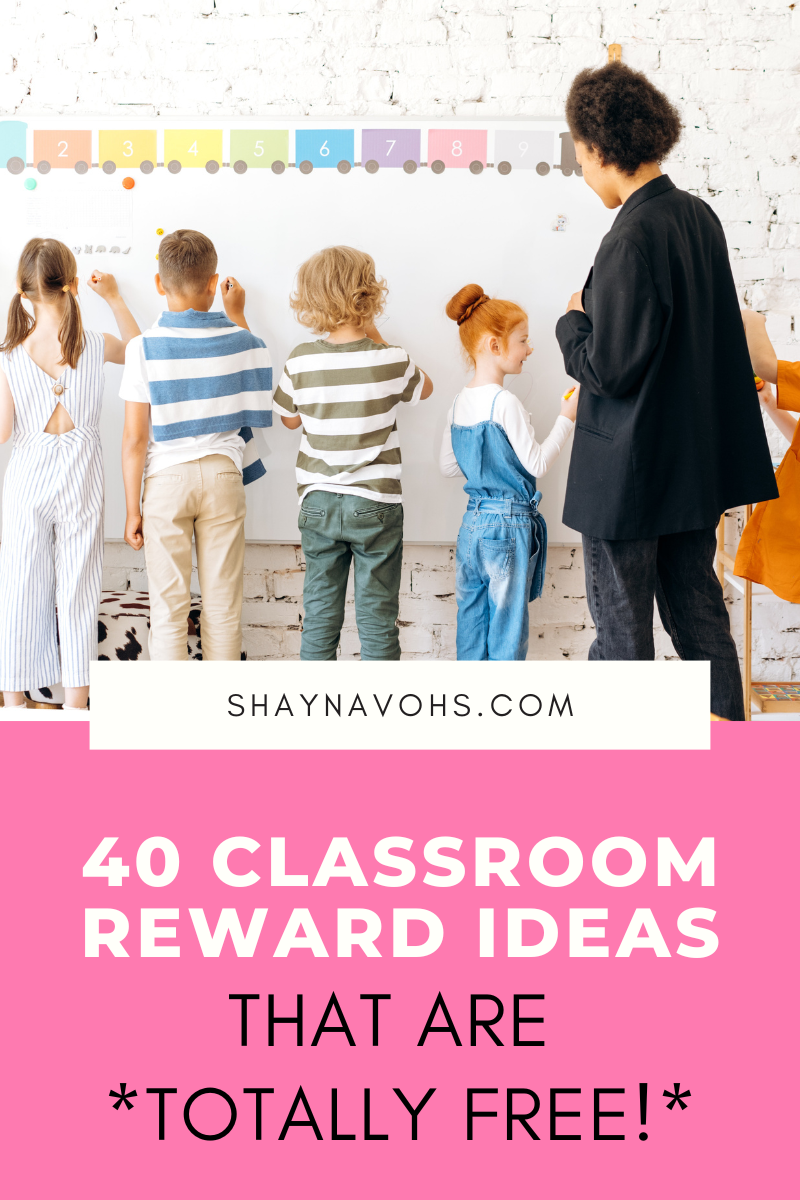 This image shows a picture of a teacher up at the front of the classroom with four other students. The students are writing on the whiteboard and the teacher is looking over their shoulders. The text on the bottom of the image reads "40 Classroom Reward Ideas that are TOTALLY FREE". 