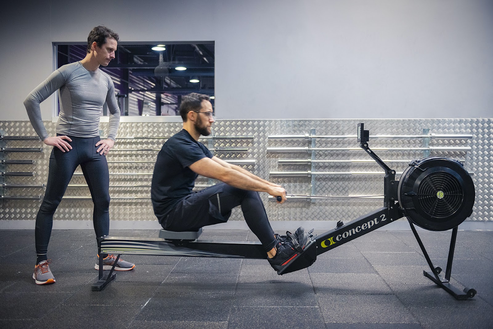 homme faisant un exercice avec un rameur et un autre homme le regarde