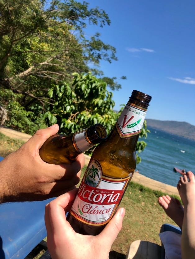Two friends holding Victoria Clasica beers at Apoyo Lagoon