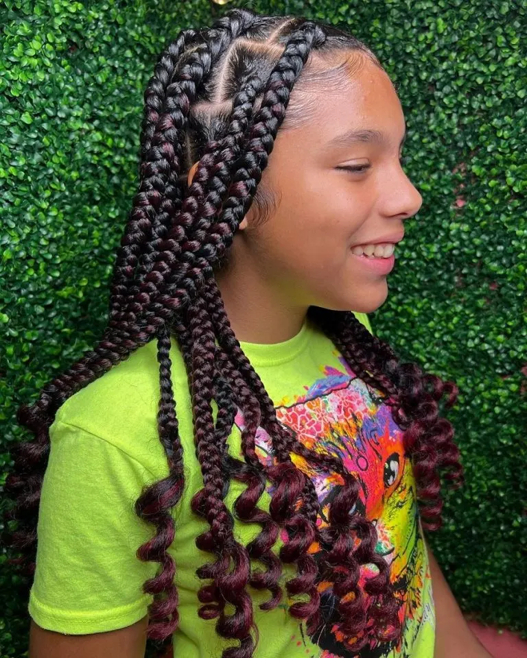 Young girl with smiles rocks her large knotless braids with curls