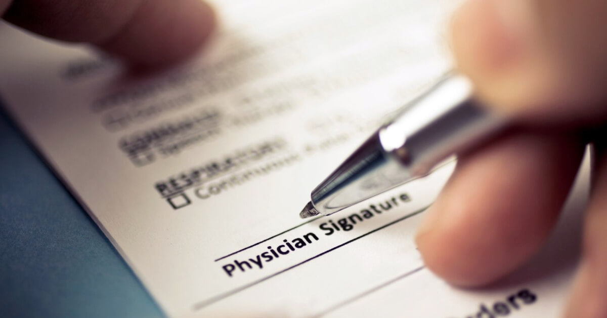 Physician signing their name on a prescription. 