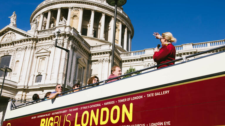 Visitors exploring things to do in London during the day from the open top of a Hop-on Hop-off bus