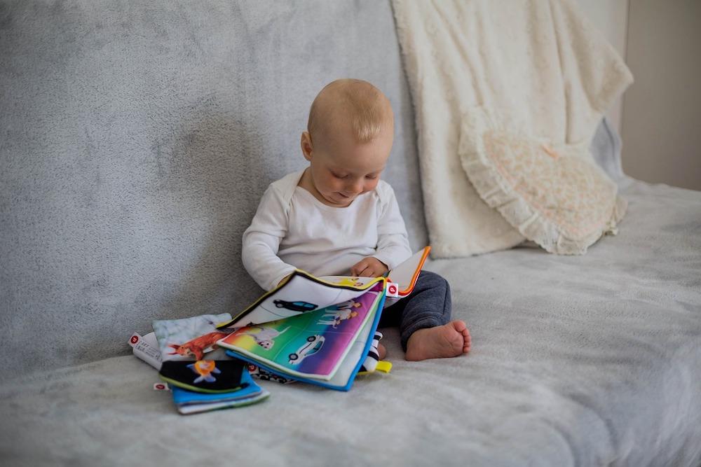 ベッドで本を読んでいる幼児中程度の精度で自動的に生成された説明