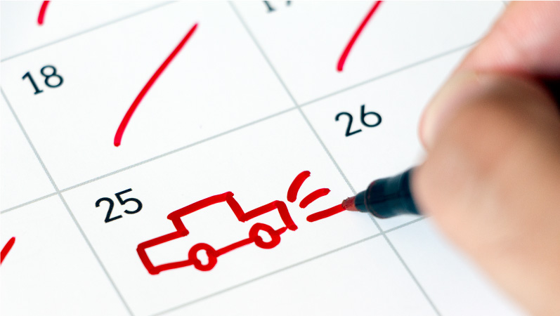 A person using a red marker to draw a simple picture of a car on their calendar to mark the day their car will be delivered by the car shipping provider