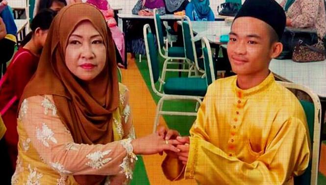 Mohd Sufie Alin, 18 tuổi, đang đeo nhẫn cưới cho vợ mình Dayang Sopiah Gusti.  /// Ảnh: The Free Malaysia Today