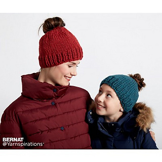 woman and child wearing knitted messy bun hats in front of white background