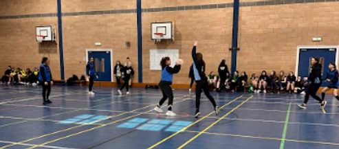 School girls playing netball in a school hall